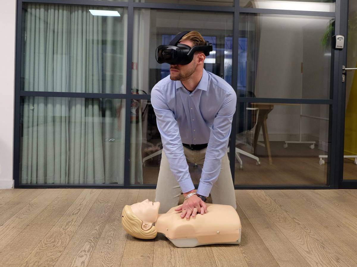 Apprenant équipé d un casque de réalité virtuelle réalisant un massage cardiaque sur mannequin connecté
